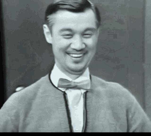 a black and white photo of a man wearing a bow tie
