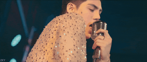 a man singing into a microphone with zky written on the bottom right