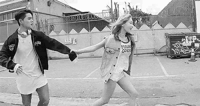 a black and white photo of a man and a woman holding hands .