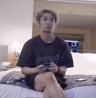 a man is sitting on a bed with his legs crossed and holding a game controller .