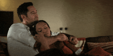 a man and woman are hugging on a couch