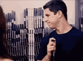 a man is standing in front of a row of hockey sticks .