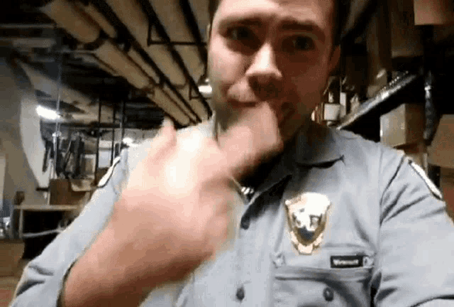 a man in a police uniform is making a funny face while covering his mouth with his hand .