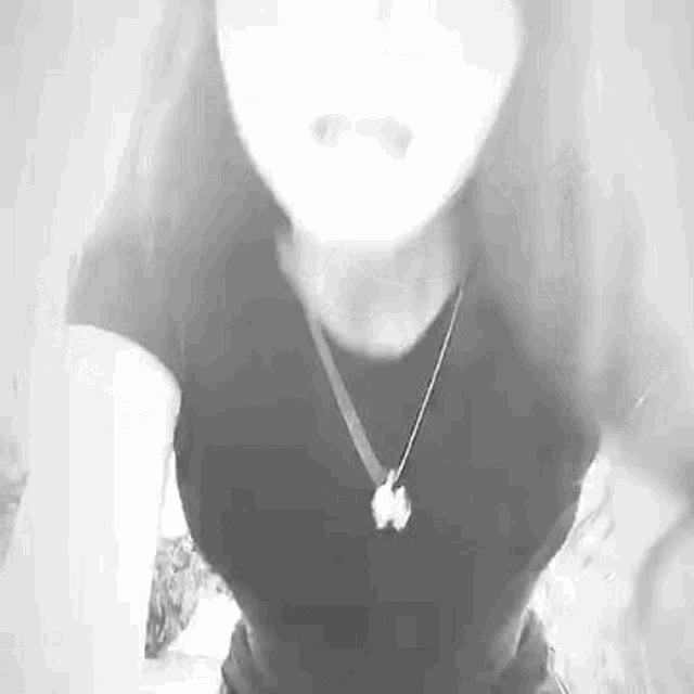 a black and white photo of a woman wearing a necklace and a t-shirt .