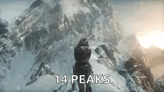 a man is standing on top of a snowy mountain .