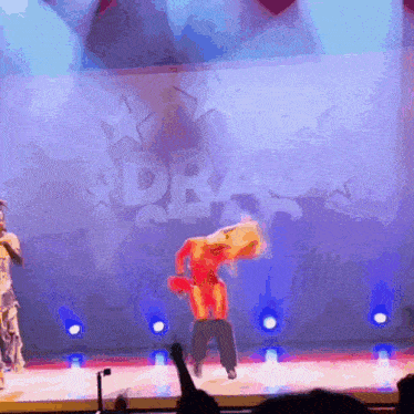 a woman is dancing on a stage in front of a sign that says ' drag ' on it