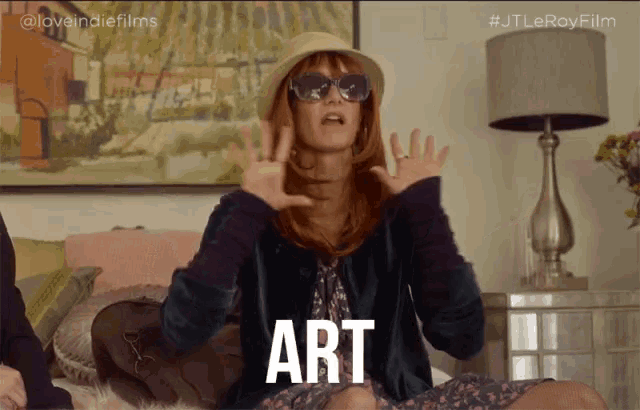 a woman wearing a hat and sunglasses says the word art