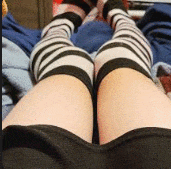 a person wearing black and white striped thigh high socks .