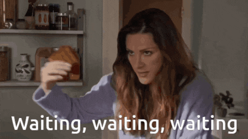 a woman sitting in front of a refrigerator with the words " waiting , waiting , waiting " above her