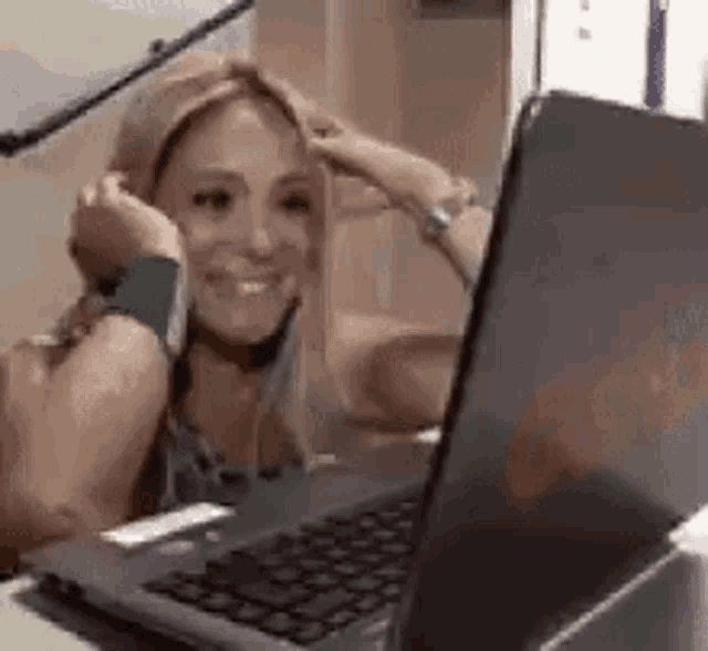 a woman is smiling while using a laptop computer .