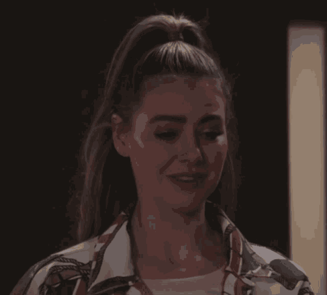 a woman with her hair in a ponytail is wearing a striped shirt