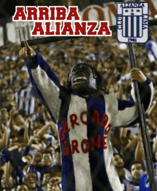 a man in a monkey costume is holding a stick in front of a crowd with the words arriba alianza above him