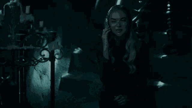 a woman in a dark room is talking on a cell phone
