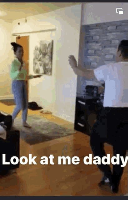 a man and woman are dancing in a living room with the words look at me daddy below them
