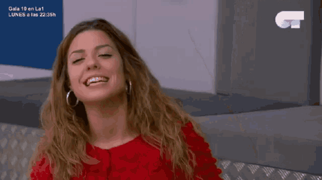 a woman in a red shirt is smiling in front of a sign that says gala 19 en la1