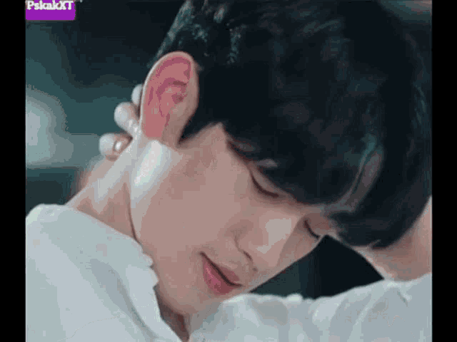 a close up of a young man 's face with his hand on his neck and ear .