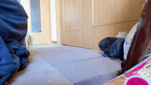 a person 's feet are on a carpet in front of a door with a bag of clothes on the floor