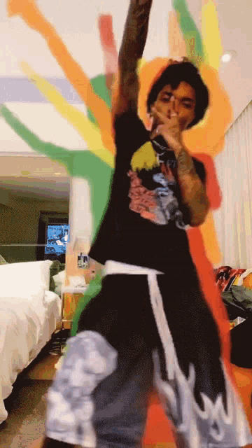 a man wearing a black shirt with a dragon on it is dancing in front of a colorful background
