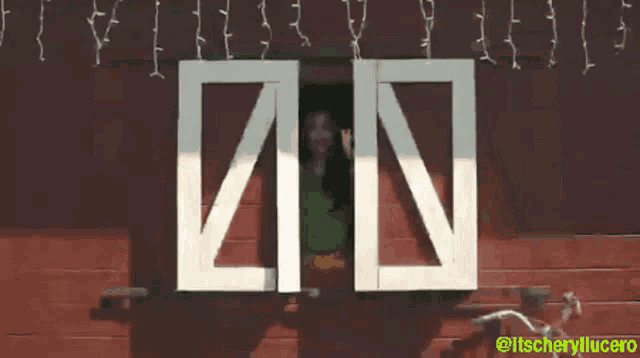 a woman in a green shirt is looking out of a window with a sign that says in