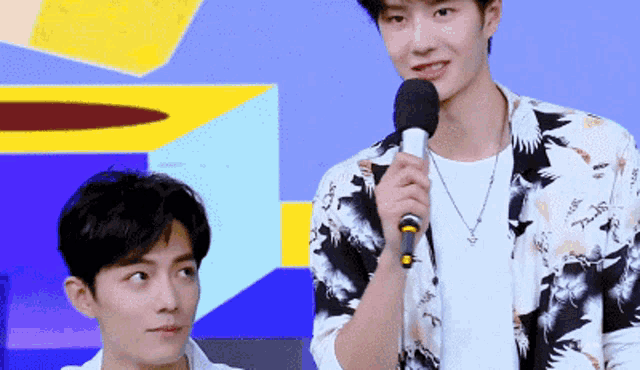 two young men are standing next to each other and one of them is holding a microphone