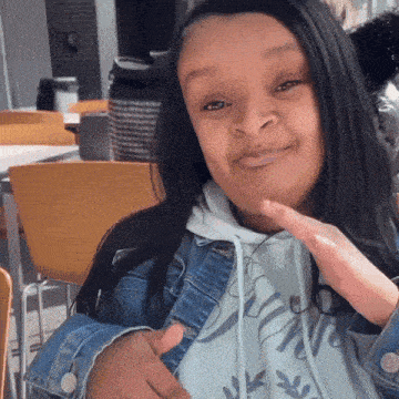 a woman wearing a denim jacket and a white hoodie that says ' jenny ' on it