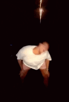 a man is dancing in a dark room with a fireworks display in the background .