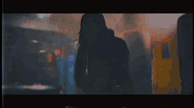 a person in a hooded jacket is standing in a dark room with smoke coming out of it .