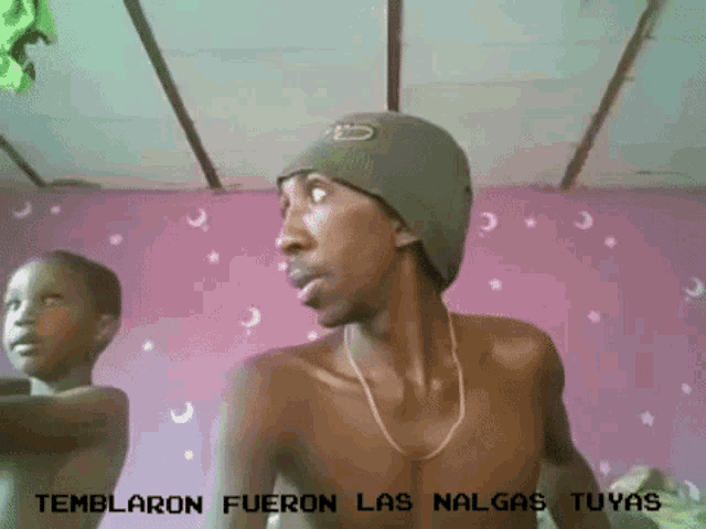 a shirtless man is standing in front of a pink wall with the words temblaron fueron las nalgas tuyas written on it