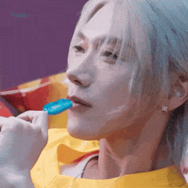 a close up of a person 's face with a blue lollipop in their mouth