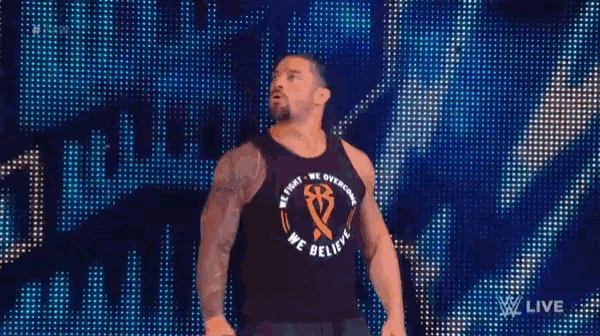 roman reigns is wearing a black tank top that says `` we fight we overcome we believe '' on it .