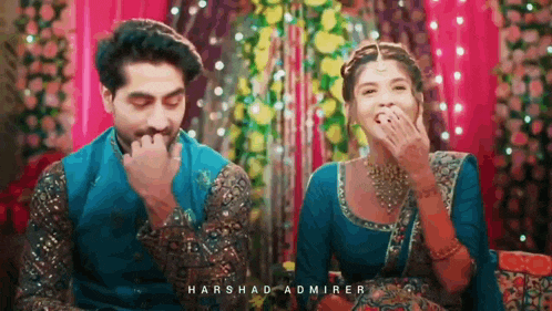 a man and a woman are sitting next to each other and laughing together .