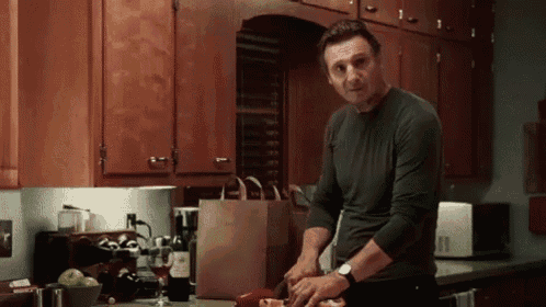a man is standing in a kitchen cutting a piece of meat