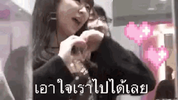 a woman is making a heart shape with her hands in front of a pixelated heart .