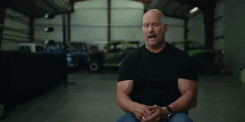 a man in a black shirt is sitting in a garage