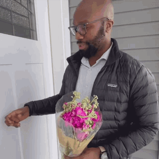 a man in a patagonia jacket holds a bouquet of flowers