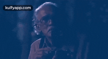 an older man wearing glasses is holding a camera in his hand .