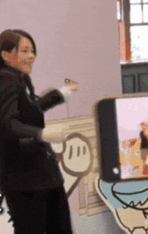 a woman in a black suit is standing in front of a cartoon drawing of a monkey