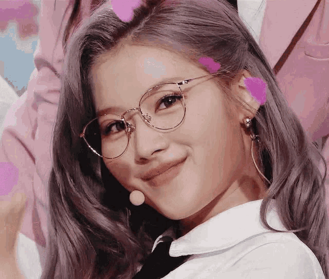 a close up of a woman wearing glasses and a white shirt .