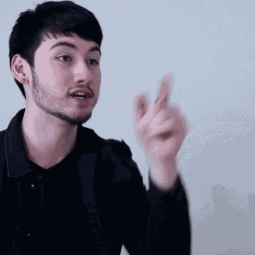 a young man with a beard is pointing his finger at the camera