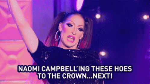 a drag queen is standing on a stage with her arms in the air and shouting .