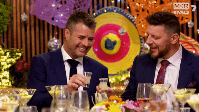 two men are sitting at a table with a sombrero in the background and a mkr rivals logo in the corner