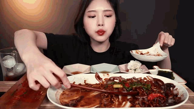 a woman is eating a large plate of food with a wooden spoon
