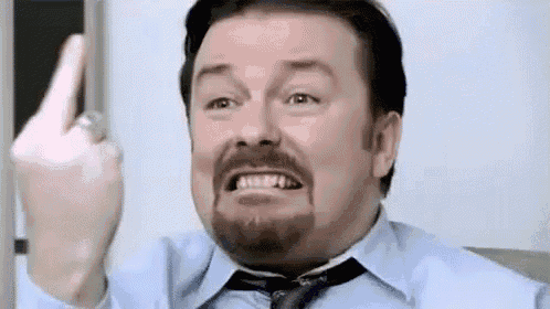 a man with a beard is wearing a blue shirt and tie and giving the middle finger .