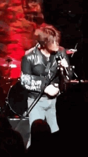 a man is singing into a microphone while holding a guitar .