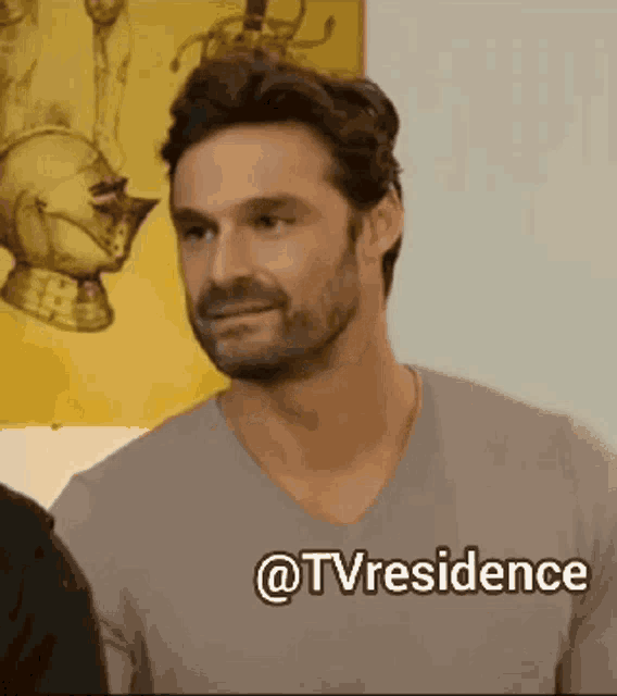 a man with a beard is wearing a grey shirt with the words @tvresidence below him