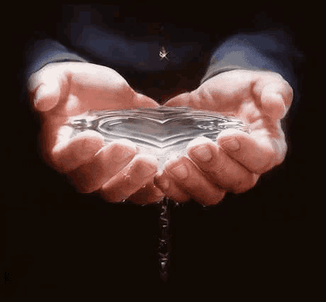 a person is holding a heart shaped drop of water .