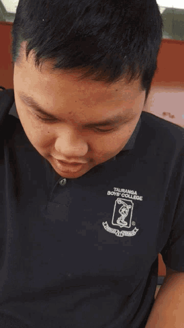 a young boy wearing a taubanda boys college shirt makes a funny face