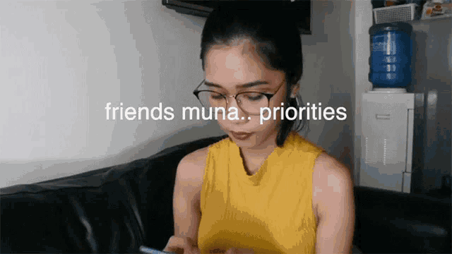 a woman wearing glasses sits on a couch with the words " friends muna priorities " above her