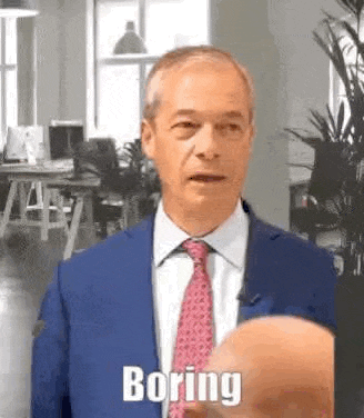 a bald man in a suit and tie is talking to another bald man in an office .