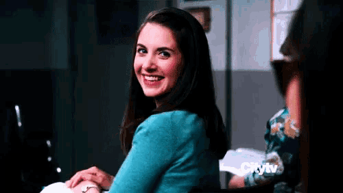 a woman in a blue sweater is smiling while sitting at a table .
